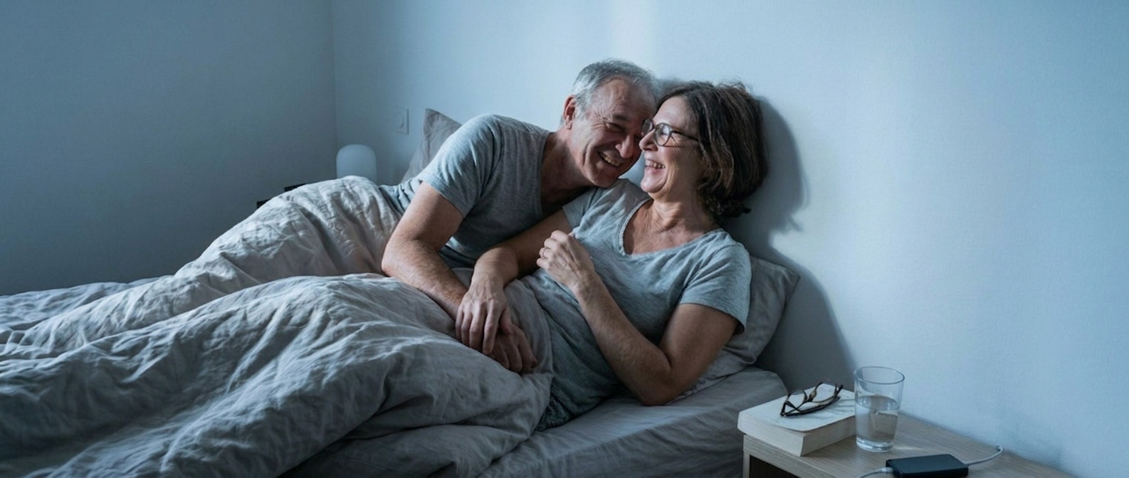 Couple senior souriant et apaisé dans leur lit, illustrant la qualité de vie retrouvée grâce au traitement du sommeil SOS Oxygène.