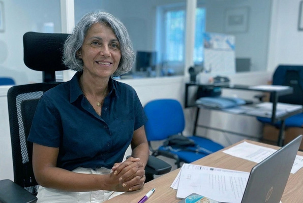 Collaboratrice SOS Oxygène souriante à son poste de travail au bureau pour l'assistance aux patients.